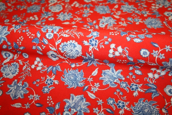 Crepevævet viskose stof med blå blomster på rød bund